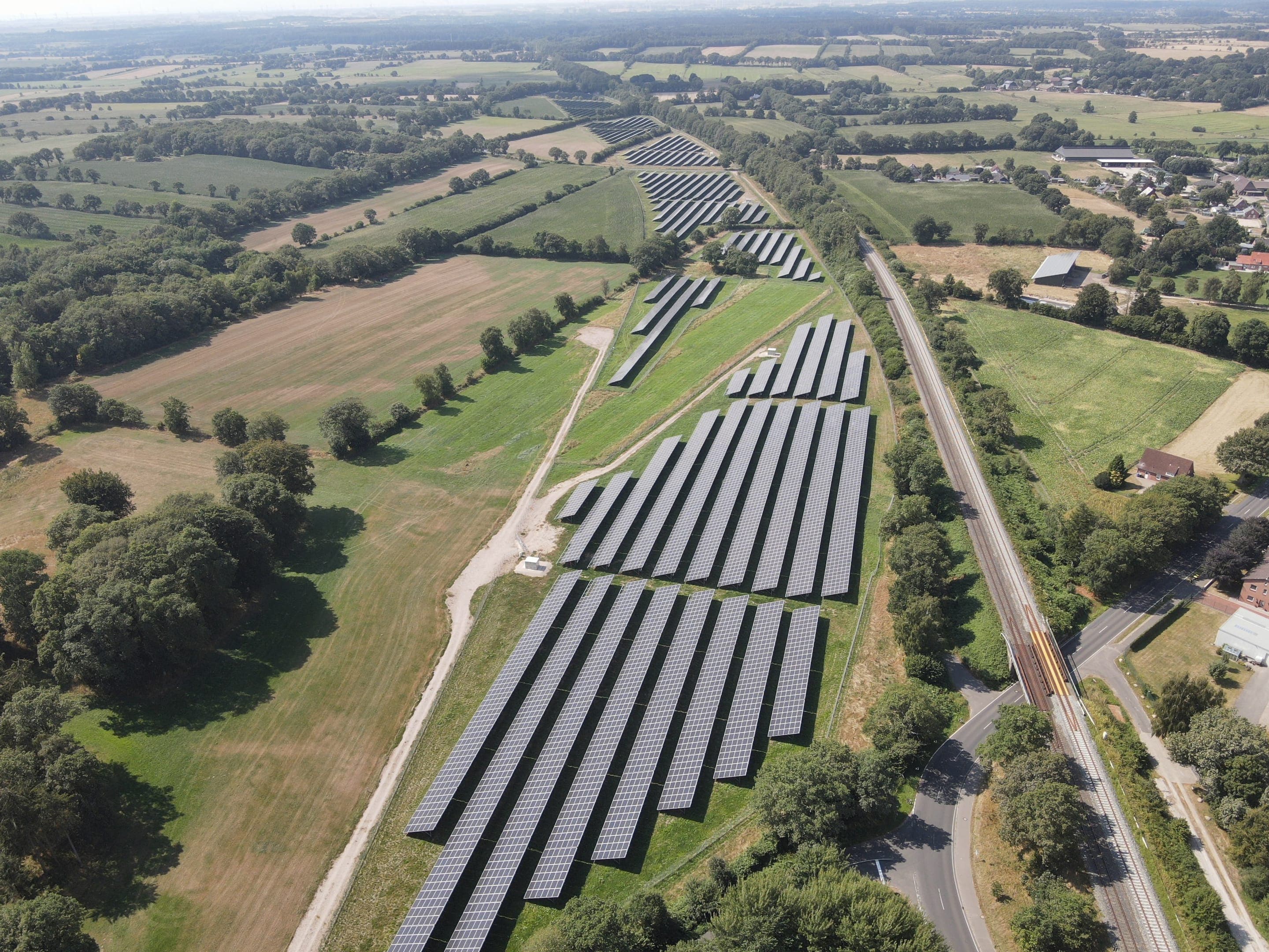 Luftbild der Photovoltaik-Freiflächenanlage Brickeln entlang einer Bahnstrecke in Schleswig-Holstein